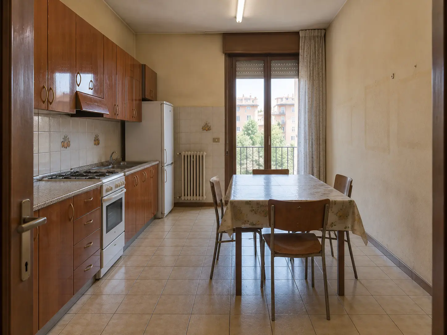 La cucina prima dei lavori: mobili in laminato ciliegio, piastrelle beige, luce al neon