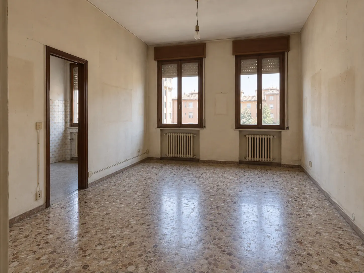 Il soggiorno prima dei lavori: graniglia consumata, pareti ingiallite, vecchi infissi in legno scuro
